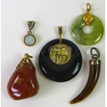A group of five pendants, comprising a late 20th century Jade bidisk, a Jet pendant similar, inset w... 