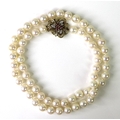A string of pearls, the 9ct gold clasp set with rubies and diamond chips, hallmarked, 30.2g.