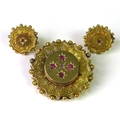 A Victorian yellow metal brooch with a pair of matching stud earrings, all set with rubies, the earr... 