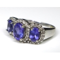 An 18ct white gold, tanzanite and diamond ring, the three oval cut tanzanites surrounded by 40 diamo... 