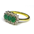 An 18ct gold, emerald and diamond ring, the three oval cut emeralds each of 5 by 4mm surrounded by 1... 