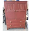 A mid 20th century linen fold cupboard with two drawers beneath, painted ox blood red and with gilt ... 