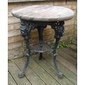 A Victorian style cast iron pub table, the black painted base with three legs, having masks to the t... 