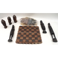 A collection of carved wooden African items, including a chess board with full set of chess pieces, ... 