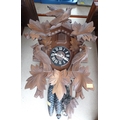 A carved wooden cuckoo clock, with birds and foliage, pine cone weights, with pendulum, 36cm.