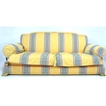 A modern three seater sofa with brass feet, yellow cotton upholstered with striped detailing.