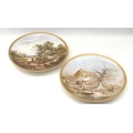 A pair of late Victorian porcelain chargers, each hand painted with a pastoral scene, one of figures... 