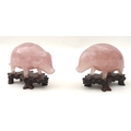 A pair of Chinese carved rose quartz pigs on hardwood stands. (2)