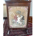 A late 19th or early 20th century glazed firescreen with needlepoint embroidered panel, 65 by 29 by ... 