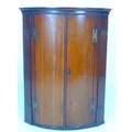 A Georgian barrel fronted corner cupboard, reeded detailing to either side of the doors, later green... 