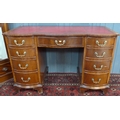 A reproduction twin pedestal desk, of bow fronted form, with red leatherette surface and nine drawer... 