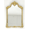 A giltwood wall mirror, late 19th / early 20th century, with shaped plate and carved frame, 52 by 84... 
