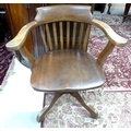 A 1930's swivel office chair, shaped rail and slat back, on four legged base with castors, possibly ... 