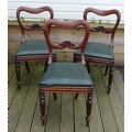 A group of three Victorian mahogany dining chairs, with shaped open backs and green drop in seats, t... 