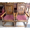A pair of oak hall chairs  the tall scroll backs carved with a portrait plaque of a woman and a man.