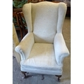 A modern Edwardian style wing armchair, cabriole front legs, pale cream patterned fabric upholstery.