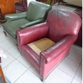 Two vintage club armchairs, one in ox-blood red leatherette, raised on short legs and brass castors,... 