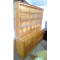 A large pine dresser, plate rack above with shaped top, the base with four drawers above pair of two... 