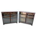 A pair of mid 20th century stained oak bookcases, each with twin leaded glazed doors enclosing two s... 
