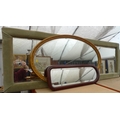 A group of three wall mirrors, one oval with gilt frame, one with green dralon frame and the third w... 