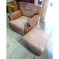 A modern brown leather armchair and footstool, with squared back and studded detail to arms, the sim... 