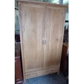 A modern oak two door wardrobe with drawer below.