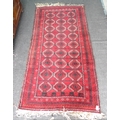 A Persian red ground rug, with nine rows of three black and white geometric medallions, multiple bor... 