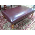 A modern burgundy leather upholstered footstool, with Victorian style turned legs and brass castors.