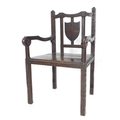 A Gothic Revival solid oak open arm chair, early 20th century, with blind carved frame, shield back,... 