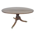 A Regency style mahogany table, with oval surface, turned column raised on three outswept legs, bras... 