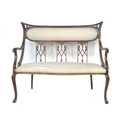 An Edwardian mahogany two seater salon settee, with carved and pierced decoration, cream foliate pat... 