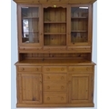 A pitch pine dresser, 20th century, with open shelves flanked by glazed cupboards, the base with six... 