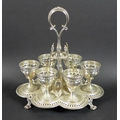 A Victorian silver egg cup stand with six egg cups, raised scroll form handle, all with pierced and ... 