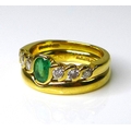 An 18ct gold, emerald and diamond dress ring in guilloche setting with six graduated diamonds to an ... 