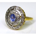 An 18ct gold, diamond and tanzanite dress ring, the central oval cut tanzanite encircled by two oval... 
