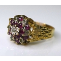 A 9ct gold, diamond and ruby flower head ring, circa 1960s, set with seven diamonds and twelve rubie... 