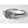 An 18ct white gold, cognac diamond and white diamond three stone ring, the central brilliant cut dia... 