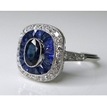 A sapphire and diamond ring, the central oval cut sapphire surrounded by a band of sapphires and an ... 