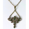 An emerald pendant of delicate scrolling design, possibly Indian, yellow and white metal setting on ... 