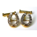 A pair of 14ct gold and diamond cufflinks formed as horseshoes, each set with seven diamonds, with r... 