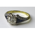 An 18ct yellow gold, diamond and sapphire dress ring, in Art Deco style, set with a central round br... 