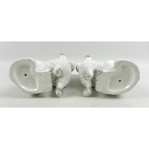 2 - A mirrored pair of Victorian Staffordshire figurines, modelled as seated poodles, with partly encrus... 