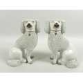 A mirrored pair of Victorian Staffordshire figurines, modelled as seated poodles, with partly encrus... 