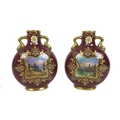 A pair of Edwardian Coalport moon flasks, with twin gilt handles, each decorated with a square reser... 