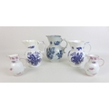 A group of five face mask jugs, comprising three blue and white decorated with sprays of flowers, Sa... 