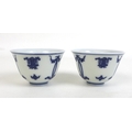 A pair of Chinese Kangxi style blue and white porcelain tea bowls, each decorated with Buddhist symb... 