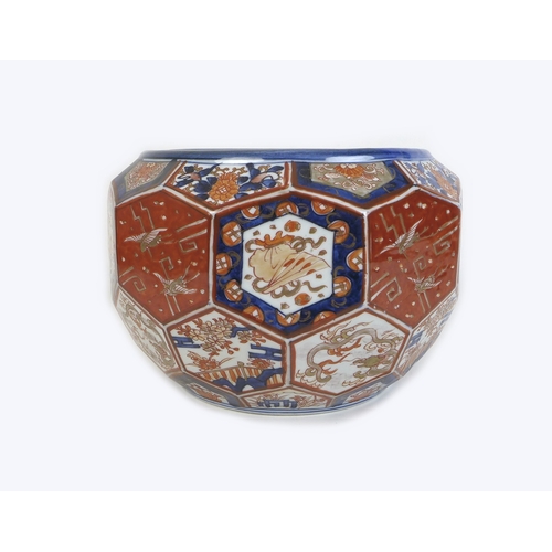 69 - A Japanese porcelain Imari pattern jardiniere, of a multi-faceted hexagonal form, decorated with cra... 