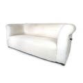 A late Victorian Chesterfield sofa, with drop arm, upholstered in white calico, raised on bun feet, ... 