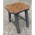 A Tramp art stool with carved wooden top and ebonised legs.