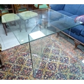 A modern glass table with square top and angled legs (in 3 pieces).